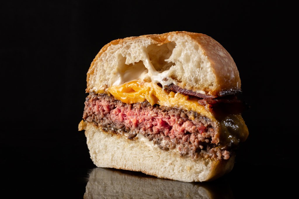 Medium rare burger cut in half against a black background