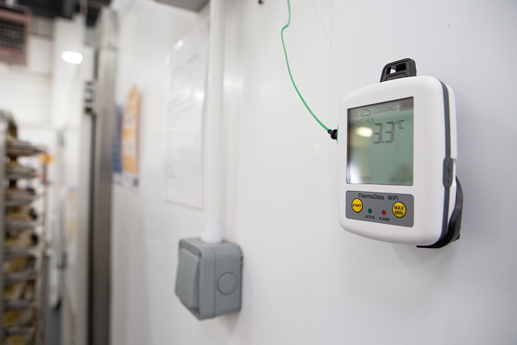 ThermaData Wi-Fi Logger affixed to the front of an industrial fridge 