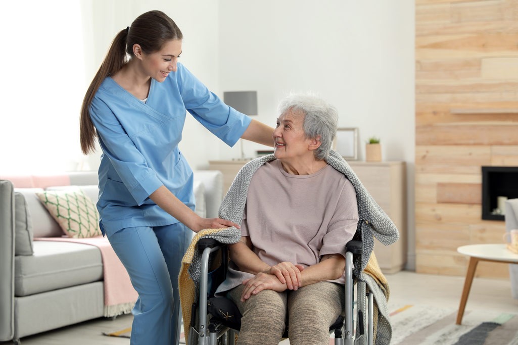Nurse covering elderly woman in a wheelchair with a blanket