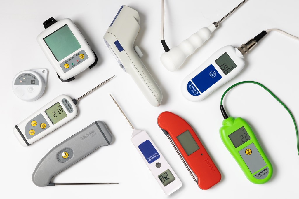 A variety of digital thermometers laying down on a white background