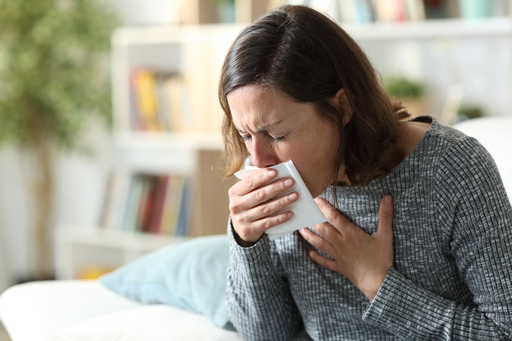 Woman coughing into a tissue