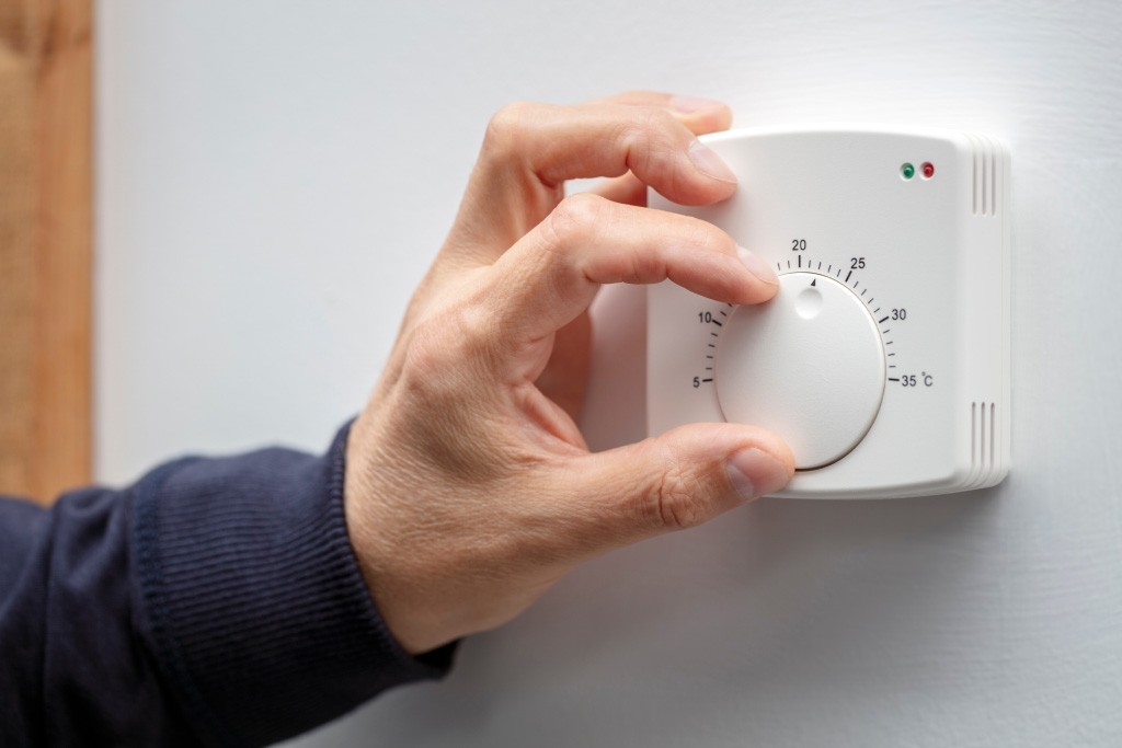 Person adjusting the temperature on their thermostat