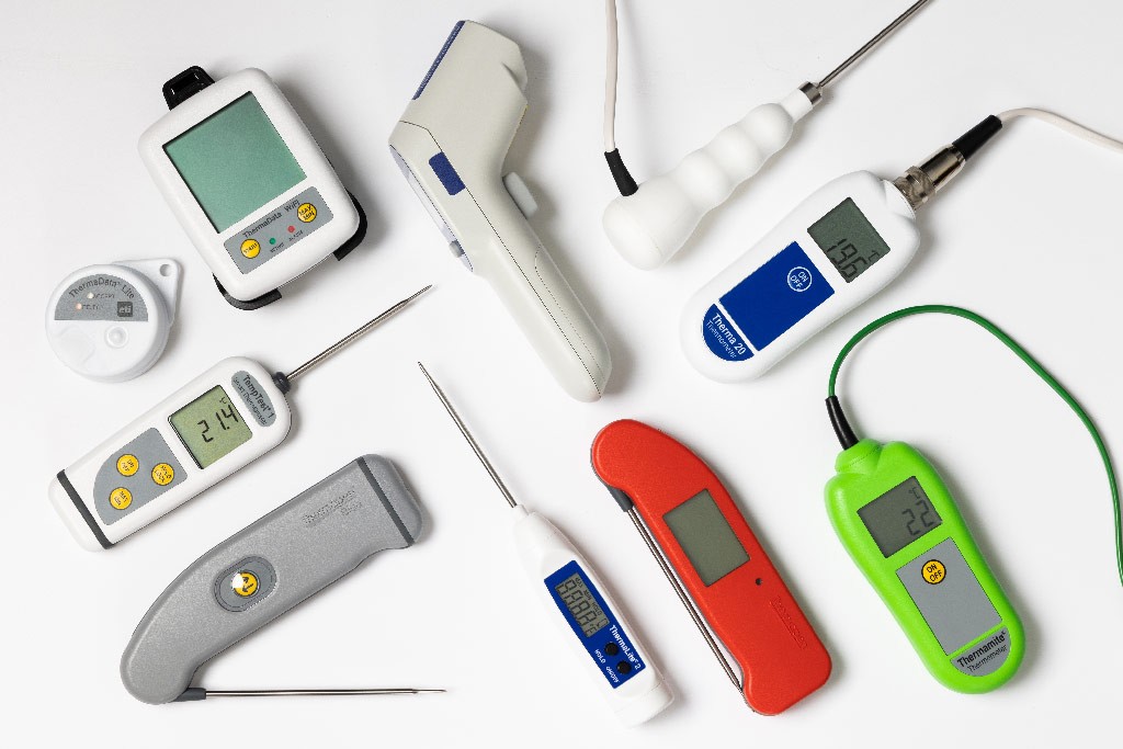 A variety of digital thermometers laying down on a white background
